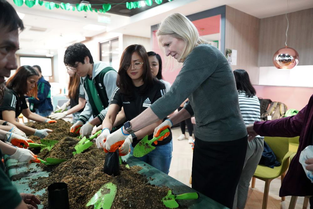 Manulife Global Chief Marketing Officer Karen Leggett joins Manulife Philippines colleague volunteers during a seedling prep activity 