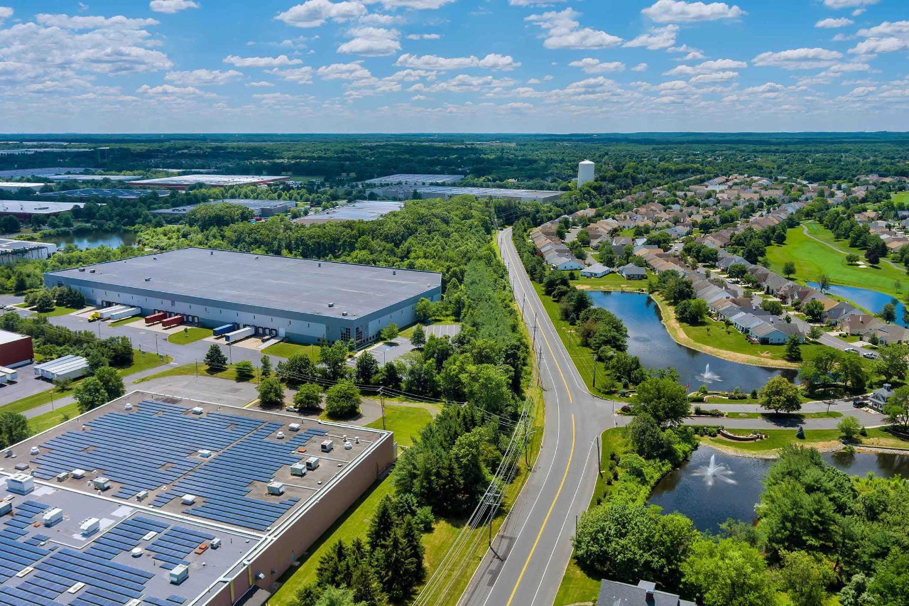 Aerial panoramic view on solar panels on absorb sunlight sustainable energy of building warehouse roof near small American town